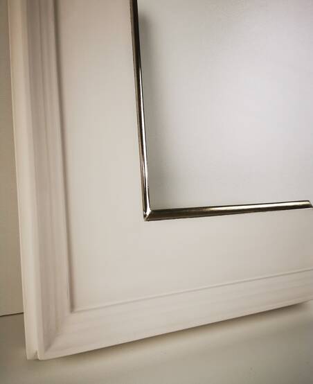 Lustro w szerokiej białej ramie ze złoconym brzegiem 22K – zbliżenie narożnika ramy.