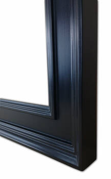 Zbliżenie narożnika dużego lustra w czarnej ramie z litego drewna