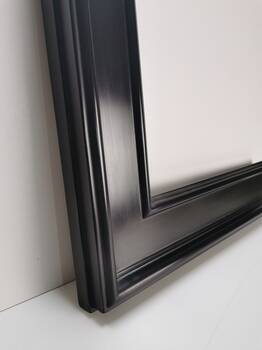 Detal powierzchni czarnej ramy lustra z delikatnym satynowym połyskiem.